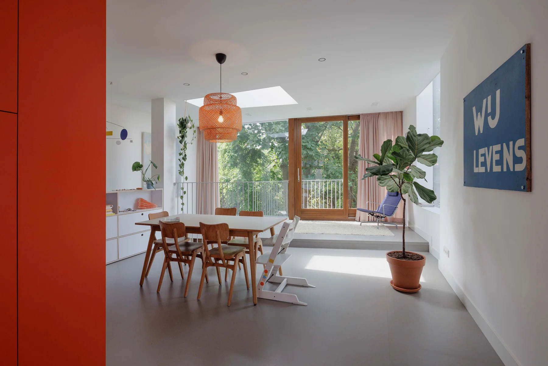 Dining and living space with red kitchen and colourful art